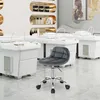A dark gray velvet office stool with wheels is placed in a beauty salon with white treatment beds and shelves in the background. Produktbild-Vorschau