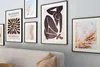A collection of framed art prints displayed on a light gray wall above a sofa. Produktbild-Vorschau