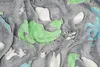A close-up view of a soft blanket with a dinosaur pattern. The blanket is gray with raised appliqués of green and blue dinosaurs, as well as white star shapes. The texture of the fabric is visible, showing its plush and soft nature. Náhled obrázku produktu