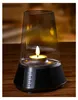 A candle inside a glass lantern sits on a wooden table. Anteprima dell’immagine prodotto