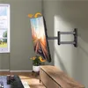 A TV wall mount is shown attached to a wall, with a TV mounted on it, angled downwards and slightly to the side. A wooden cabinet is below the TV, and a window is visible to the left. Produktbild-Vorschau