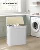 A white laundry basket filled with clothes sits in a laundry room next to a washing machine. Podgląd zdjęcia produktu