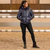 A woman stands in an indoor riding arena, wearing a puffer jacket and leggings. Voir les images du produit