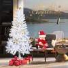 A baby dressed as Santa sits on a chair next to a white Christmas tree, with gifts at the base of the tree. The scene is set in a room with a large window overlooking a body of water and mountains. Voir les images du produit