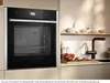 A modern kitchen scene featuring a built-in oven and a countertop with a sink and decorative items. Produktbild-Vorschau