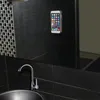 A smartphone is attached to a tiled wall above a sink and faucet in a modern bathroom. Produktbild-Vorschau
