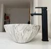 A close-up shot of a marble-patterned sink and a black faucet on a white countertop. Náhľad obrázku produktu
