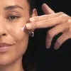 A close-up shot of a woman applying cream to her face. Náhľad obrázku produktu
