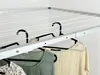 A close-up view of a ceiling-mounted clothes drying rack with clothes hanging on it. Voir les images du produit
