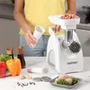 A person is preparing to use a meat grinder, with ingredients and accessories laid out on a counter. Produktbild-Vorschau
