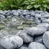 Grau gemaserte Kieselsteine als dekorative Umrandung eines kleinen Gartenteichs oder Wasserbeckens Produktbild-Vorschau