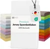A stack of folded white bed sheets is shown in the foreground, with a stack of colorful folded bed sheets in the background. A product tag is attached to the white sheets. Produktbild-Vorschau