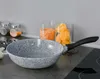 A speckled gray frying pan with a black handle sits on a dark countertop next to jars of lentils and pasta. Náhľad obrázku produktu