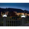 Two solar-powered fence post lights illuminate a dark yard in front of a large house. Produktbild-Vorschau