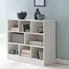A white bookshelf filled with books and decorative items, set against a light blue wall. Produktbild-Vorschau