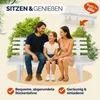 A family is sitting on a white garden bench in an outdoor setting with green trees in the background. Náhled obrázku produktu