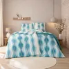 A bedroom scene with a bed made up with blue and white wave-patterned bedding. Produktbild-Vorschau