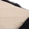 A close-up view of the underside of a dark gray sheepskin cushion, showing the quilted beige fabric backing. Podgląd zdjęcia produktu