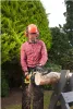 A man wearing safety gear is using a chainsaw to cut a log in a garden. Anteprima dell’immagine prodotto