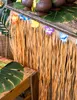 A close-up of a table decorated for a Hawaiian party, featuring a grass skirt table skirt adorned with colorful flowers. Podgląd zdjęcia produktu