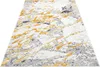 A close-up, angled view of a rug with a marble-like pattern in shades of white, gray, and gold. Produktbild-Vorschau
