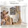 A family with a baby in a nursery setting, with a wall shelf displaying toys. Produktbild-Vorschau
