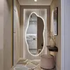 A hallway with a large, irregularly shaped mirror with LED lighting, a small shelf with a vase, and a stool. Produktbild-Vorschau