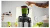 A person is pouring liquid into a blender filled with a green smoothie. Náhled obrázku produktu
