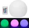 A white spherical LED lamp with a remote control, shown with different color lighting options. Náhľad obrázku produktu