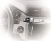A close-up shot of a car's dashboard with a Bluetooth hands-free device mounted on the vent. Produktbild-Vorschau