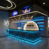A modern bar area with a prominent illuminated bar counter, stools, and shelves stocked with bottles. Anteprima dell’immagine prodotto