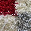 A close-up view of a shaggy rug with a checkered pattern in red, gray, and cream colors. Produktbild-Vorschau