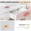 Close-up of a white vanity drawer with a diamond-shaped handle, and a hand reaching for it. Text overlays describe the drawer and handle. Produktbild-Vorschau