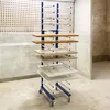 A drying rack with multiple shelves holding various wooden panels and cabinet doors, likely in a workshop or painting area. Anteprima dell’immagine prodotto