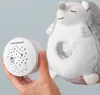 A hand holds a white projector device next to a plush hedgehog toy. Voir les images du produit