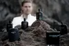 Several bottles of men's fragrance are arranged on rocks, with a man in the background. Voir les images du produit
