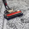 A vacuum cleaner head is shown cleaning a patterned rug. Produktbild-Vorschau