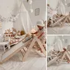 A child playing on a wooden climbing structure in a nursery. Anteprima dell’immagine prodotto