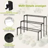A black metal plant stand with three tiers, shown with illustrative callouts highlighting its features. The background is a light cream with floral illustrations. Podgląd zdjęcia produktu