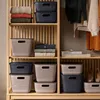 Storage baskets and folded clothes on shelves in a closet. Produktbild-Vorschau