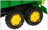 A close-up view of the wheels and lower body of a green toy tractor trailer. Produktbild-Vorschau