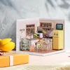A miniature dollhouse kitchen scene with a yellow refrigerator, stove, sink, dining table, and various accessories. Podgląd zdjęcia produktu