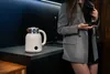 A woman in a suit holds a cup of coffee in a modern kitchen. Podgląd zdjęcia produktu