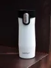 A white Contigo travel mug with a black lid sits on a textured brown surface. Anteprima dell’immagine prodotto
