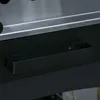 A close-up view of a black handle on a grill. Produktbild-Vorschau