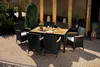 An outdoor dining set with a table and chairs on a paved patio, surrounded by greenery. Náhľad obrázku produktu