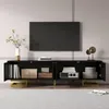 A black TV stand with gold legs and handles, featuring open compartments displaying books, boxes, and decorative items. A large black TV is mounted on the wall above the stand. Anteprima dell’immagine prodotto