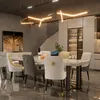 A modern dining room with a marble-top dining table and upholstered chairs, illuminated by a contemporary chandelier. Voir les images du produit
