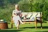 A woman reads a book on a bench in a garden with her dog. Produktbild-Vorschau