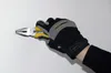 A gloved hand holding a pair of pliers against a white wall. Produktbild-Vorschau